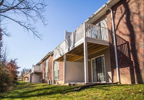 a brick building with a balcony and a green yard